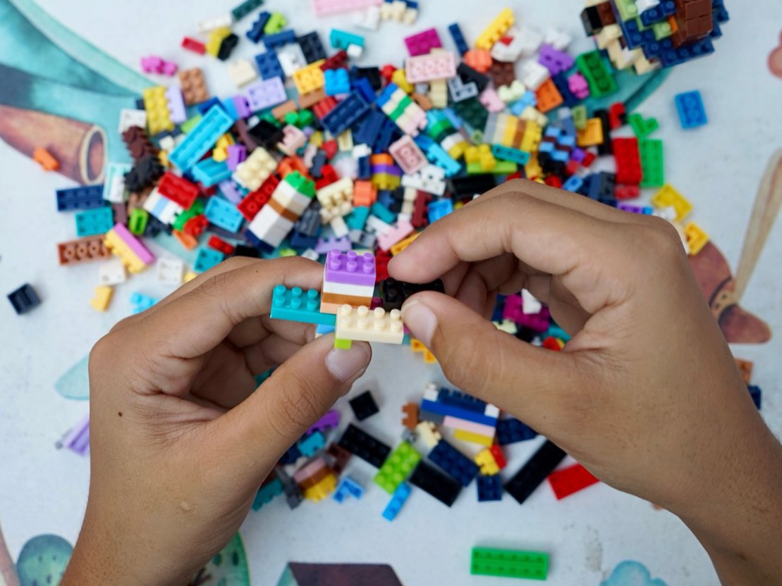 A child's hands assembling colorful LEGO bricks